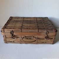 Full front view of the rectangular bamboo basket with closed lid, showing the handle and toggle closures.
