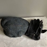 Harris Tweed wool cap and brown Roots leather gloves on marble surface, showing overall items together