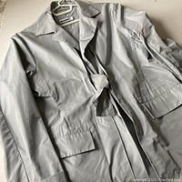Front angled view of Jil Sander silvery grey lightweight jacket with tie belt and long sleeves.