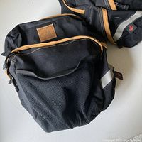 Pair of black and brown Arkel bicycle pannier bags showing mesh pockets and zipper compartments.