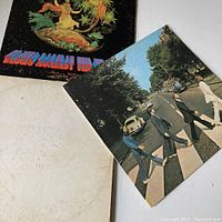 Three vinyl record albums arranged to show covers of Jefferson Starship 'Blows Against The Empire', The Beatles Abbey Road, and The Beatles White Album with visible wear