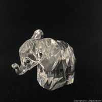Side view of the clear faceted crystal elephant figurine showing detailed ears, curled trunk, and compact body.