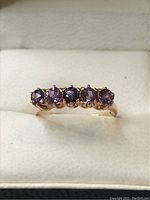 Front view showing five round purple amethysts set in a yellow gold band