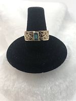Full front view of ring on black stand showing bezel-set aquamarine and filigree band