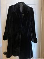 Front view of closed coat showing rounded collar and single button closure