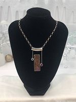 Full view of necklace on black display bust showing chain and pendant