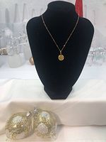 Necklace displayed on black bust with holiday decorations visible behind