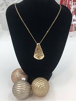 Front view of necklace on black bust with decorative spheres in foreground