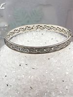 Top view of Celtic sterling silver bangle on white crystal background