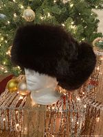 Front three-quarter view of dark brown fox fur ushanka hat on mannequin head