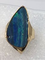 Top-down view showing freeform boulder opal with blue-green play-of-color set in gold bezel
