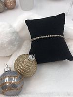 Full view of sterling silver diamond tennis bracelet displayed on black cushion with decorative ornaments