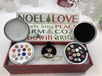 Overview of two snap button charm storage boxes showing a total of 18 charms, plus ring on stand, bracelet and chain with pendant in wooden tray