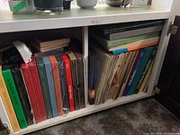 Shelf with more than twenty vinyl records and boxed music sets, stacked vertically and horizontally, including classical and jazz collections.