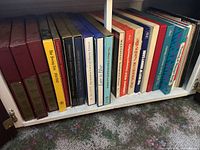 Shelf with around 15 boxed sets and songbooks mostly in burgundy, blue, orange, and yellow.