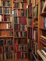 Bookshelves filled with a diverse collection of hardback books, primarily vintage or classic editions, spanning multiple rows and shelves.
