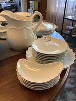Porcelain plates stacked with a large white Ridgeways pitcher beside them on table.