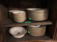 Shelf with stacked Limoges china: soup bowls, dinner plates, salad plates, showing their size and arrangement.