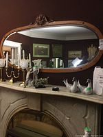 Front view of oval wood framed mirror mounted over fireplace mantel
