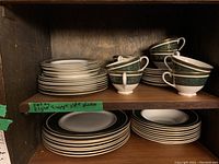 Top shelf view showing stacks of plates and sets of teacups in matching pattern.