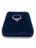 Front view of CZ ring on black velvet pad showing center square-cut stone and band with small CZ stones.