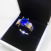 Front angled view of men's blue gemstone ring showing rectangular stone and side accent stones in black velvet box.