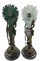 Pair of female warrior bronze statues standing side by side on round bases, showing both green and white patina versions.