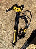 Full view of the Charlet Moser ice axe laying on wooden surface, showing black and yellow handle and attached leash.