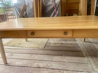 Side view of coffee table showing the drawer with two round knobs and the natural wood grain finish