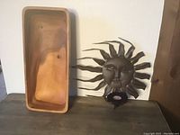 Photo shows the wooden bowl placed vertically and the metal sun wall hanging with the blue glass votive holder attached below.