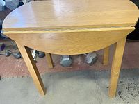 Top-down view showing table with drop leaf folded down revealing wear and discoloration on tabletop surface.