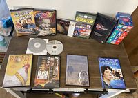 Display of assorted DVDs and Wallace and Gromit VHS tape sets arranged on a table, showing variety of movie titles and formats.
