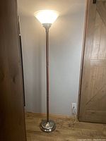 Full view of the floor lamp standing 72 inches tall with wood look finish and metal base, plugged in and turned on.
