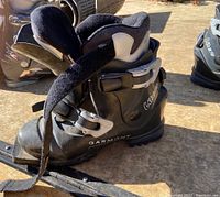 Front-left side view of one black Garmont backcountry ski boot showing the boot's shape, buckle, strap, and inner lining.