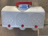 Front view of white OverEZ chicken waterer with barn detail and red drip-free nipples.