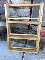 Front view of the wooden spice rack showing all four shelves and natural wood finish.