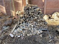 Photo of a large, neatly stacked pile of rectangular and square new stone siding pieces in natural earth tones outdoors