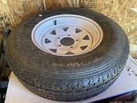 A 13-inch Towmax tire mounted on a white metal rim inside a wooden structure.