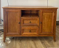 Front view of wood veneer TV console with two drawers and two enclosed cabinets.
