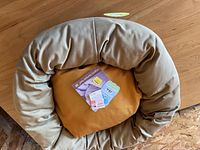 West Paw Organic Bumper Bed with light tan padded bumper and mustard yellow cushion shown from top view with tags inside.