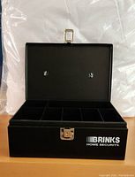 Open view of black Brinks cash box showing multiple compartments for organizing coins and bills.
