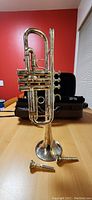 Jupiter C trumpet standing upright on table with detached mouthpieces and case behind