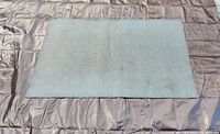 Silver rectangular rug showing basketweave texture laid flat on quilted surface.