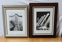 Front view of two framed black and white archival photo reproductions: left is Golden Gate Bridge construction circa 1936, right is Grand Central Terminal NYC circa 1930.