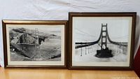 Pair of framed archival black and white prints depicting Golden Gate Bridge construction circa 1936, placed side by side on cloth background.