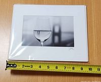 Photo of the front of the black and white photograph showing the wine glass with the Golden Gate Bridge reflection and the artist's signature on the mat.