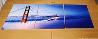 Front view of three triptych panels displaying connected Golden Gate Bridge image with fog and blue sky.