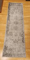 Top down view of rectangular grey runner rug showing overall size and pattern on wooden floor.