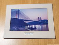 Matted photo of Tsing Ma Bridge showing bridge and water at dusk with label under the photo.