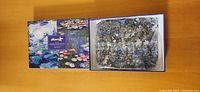 Box of Monet double-sided 500-piece puzzle with Water Lilies designs, showing box cover and bag of pieces inside.